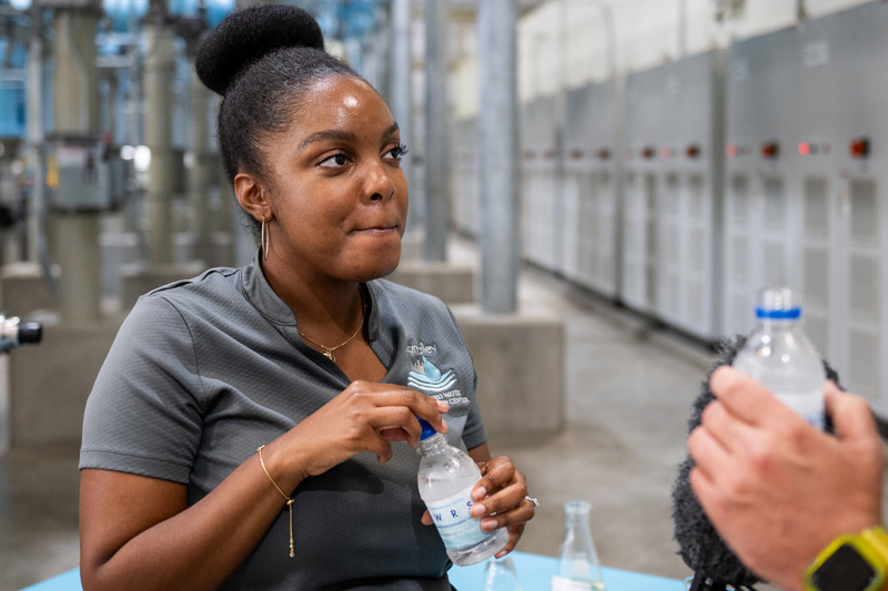 Lakeisha Bryant, of Valley Water, samples a bottle of recycled water at Silicon Valley Advanced Water Purification Center in San José on Aug. 14, 2023. (Beth LaBerge/KQED)